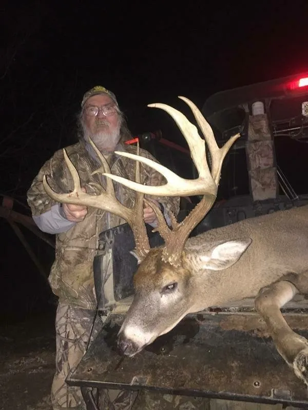 Robin Gassett holding the antlers of a large white-tailed deer buck